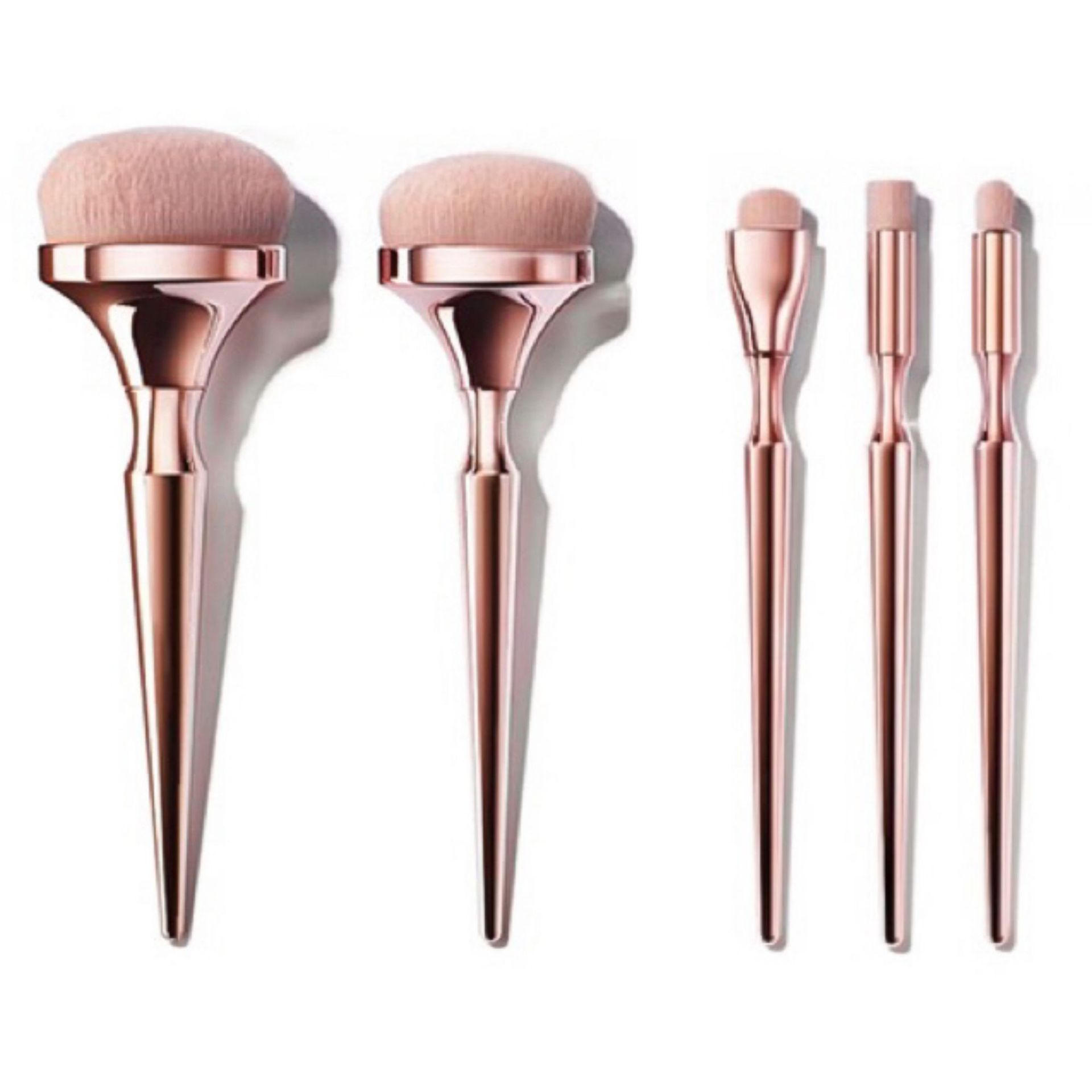 Five makeup brushes with rose-gold metallic handles and soft pink bristles, arranged against a white background.