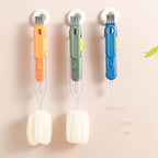 Orange, green, and blue 5-in-1 detachable plastic cup brushes with sponges hanging on a wall.