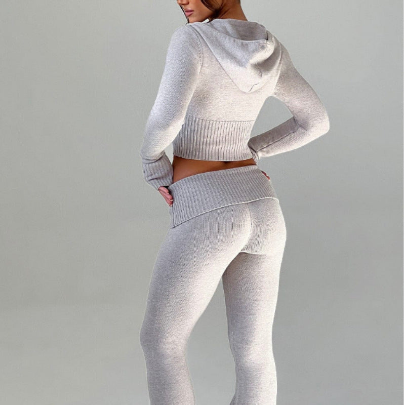 A woman wears a light gray knit slim-fit matching set, featuring a cropped hooded top and high-waisted leggings.