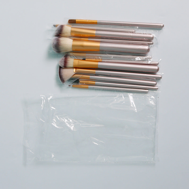 Set of 12 makeup brushes with champagne handles, gold ferrules, and soft synthetic bristles in a plastic bag.