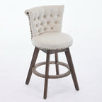 Beige tufted velvet swivel bar stool with nailhead trim and brown wooden legs on a white background.