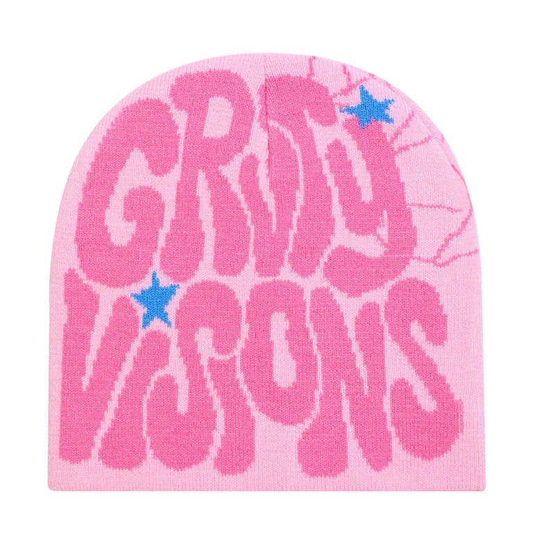 Pink knit beanie with bold "GRSY VISONS" text, spiderweb detail, and small blue star accents.