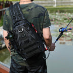 A black camo tactical sling backpack with MOLLE webbing, D-rings, and gear attachments on a person fishing.
