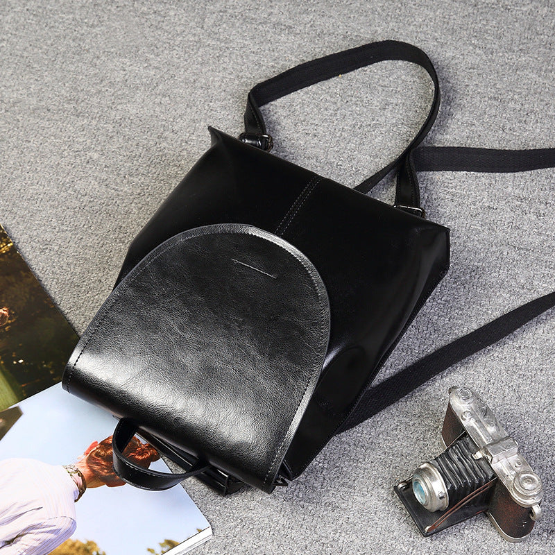 Black genuine leather women's messenger-style backpack with a flap top and adjustable fabric straps.