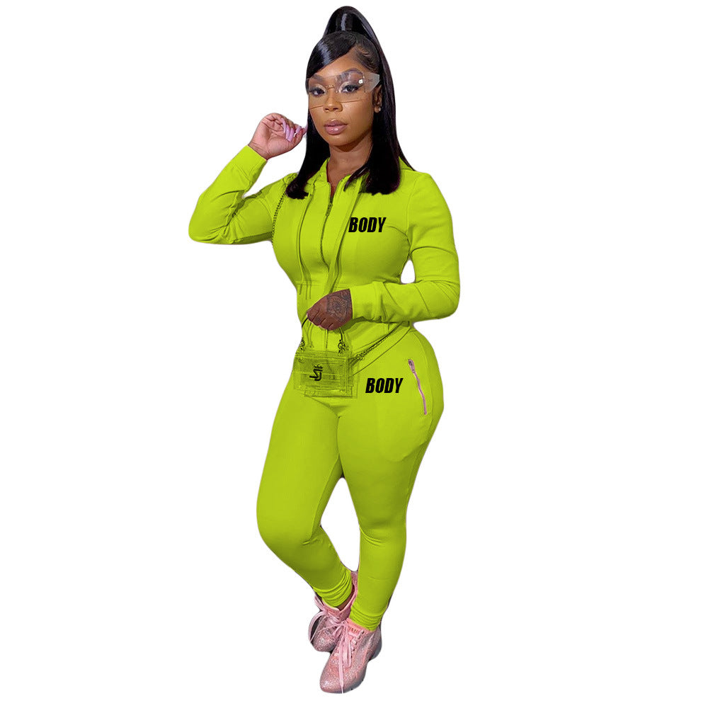 A lime green zippered hooded jumpsuit with "BODY" text prints and matching bag, worn by a woman with pink sneakers.