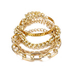A stacked set of gold-tone hip hop bracelets, featuring Cuban links, twisted ropes, and a sleek metal bangle.