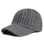 Grey knitted wool baseball cap with cable-knit detailing and a ribbed brim, set against a plain white background.