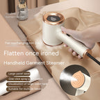 A handheld, cream and gold portable garment steamer being used on tan fabric, featuring a sleek, modern design.