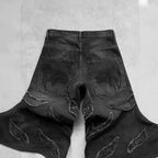 Black baggy denim jeans with frayed patchwork detailing and embroidered gothic script on the back pockets.