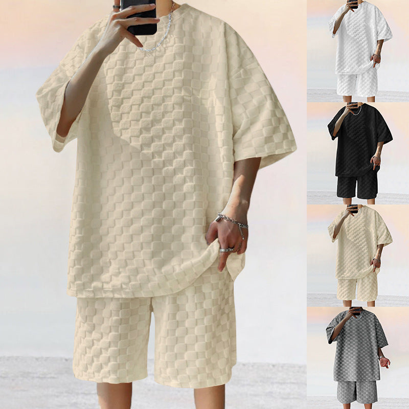 A model wears a loose, textured jacquard plaid shorts set, available in cream, white, black, and gray.