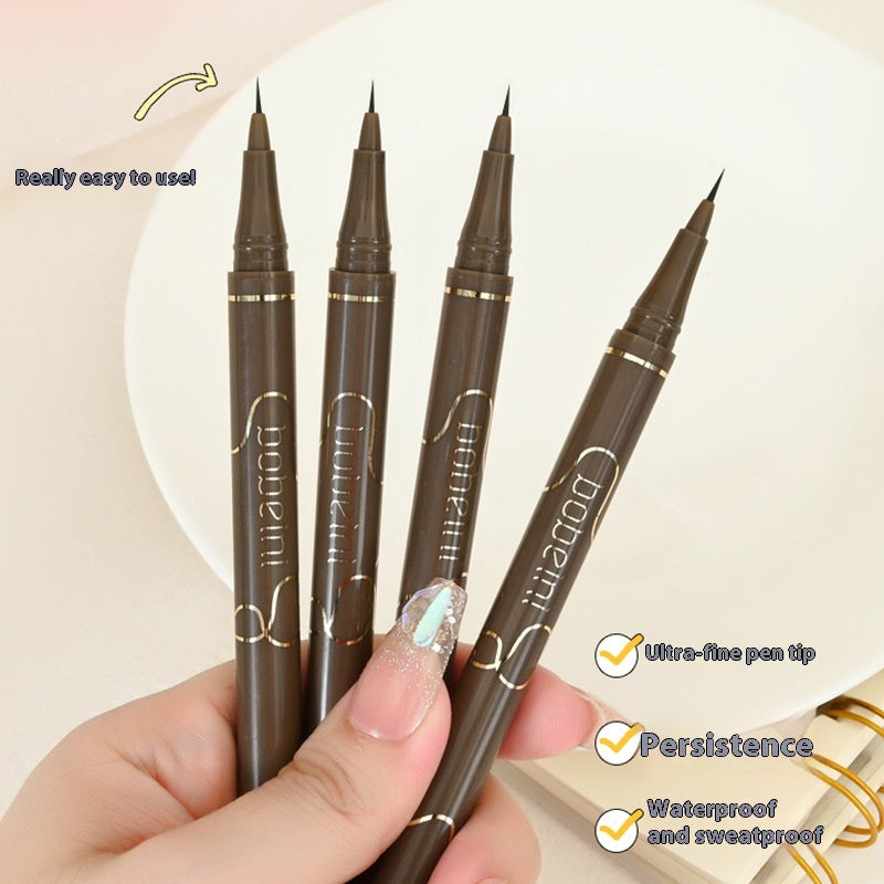 A hand holds four slim brown eyeliner pens with gold lettering, featuring ultra-fine tips for precise application.