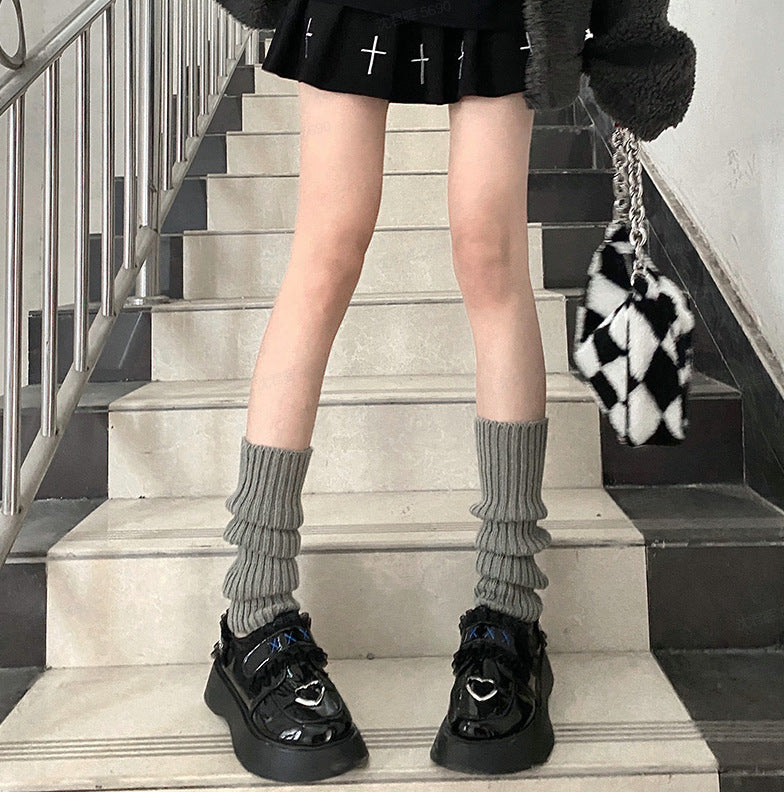 Grey ribbed knit slouchy leg warmers worn with black platform shoes on a staircase.