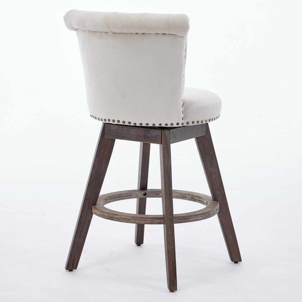 Beige tufted velvet swivel bar stool with nailhead trim and brown wooden legs on a white background.