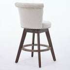 Beige tufted velvet swivel bar stool with nailhead trim and brown wooden legs on a white background.