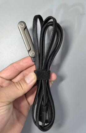 Black braided 2-in-1 fast charging cable with integrated metallic foldable phone stand held by a hand.