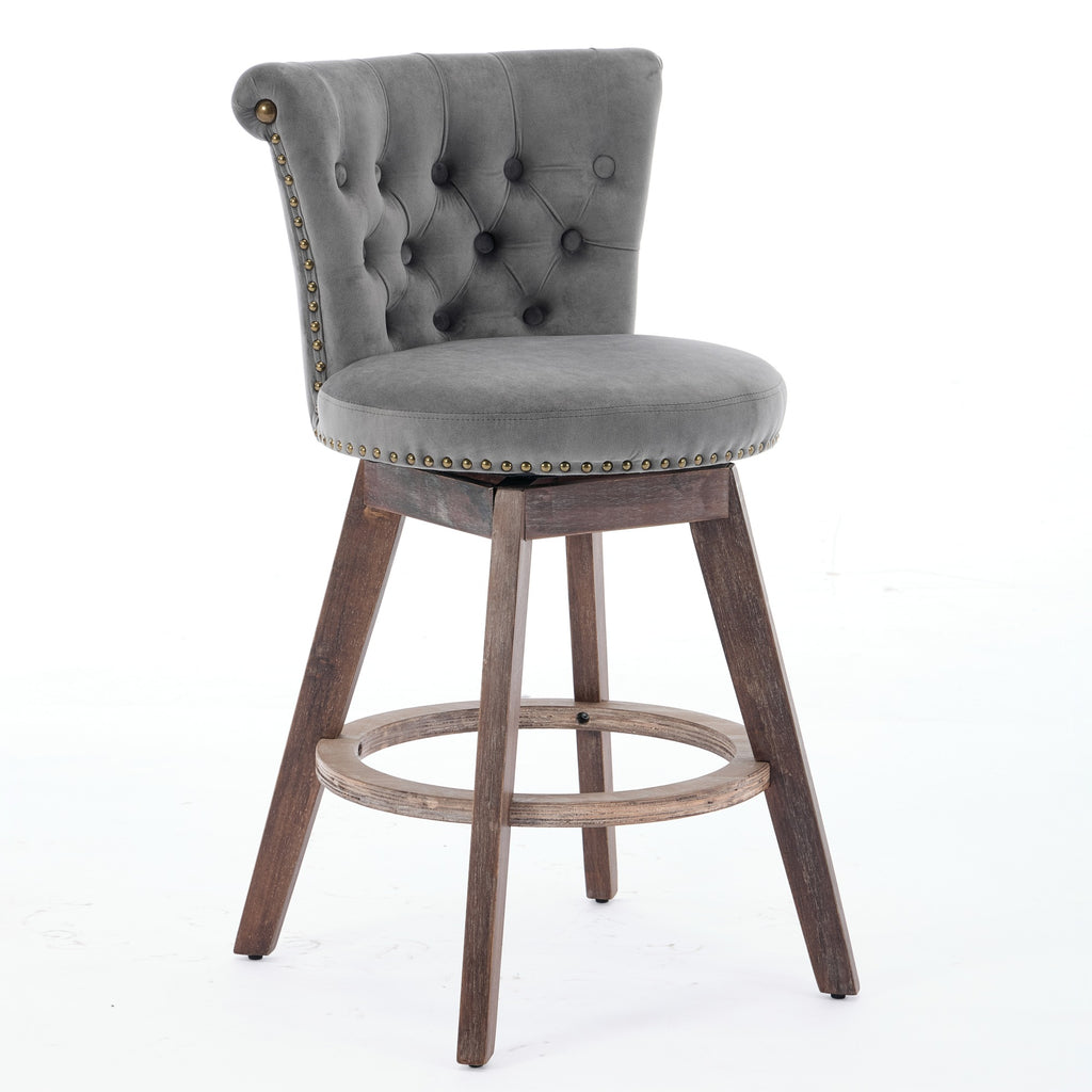 Gray velvet counter stool with tufted back, nailhead trim, and dark wood legs with a round footrest on a white background.