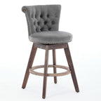 Gray velvet counter stool with tufted back, nailhead trim, and dark wood legs with a round footrest on a white background.