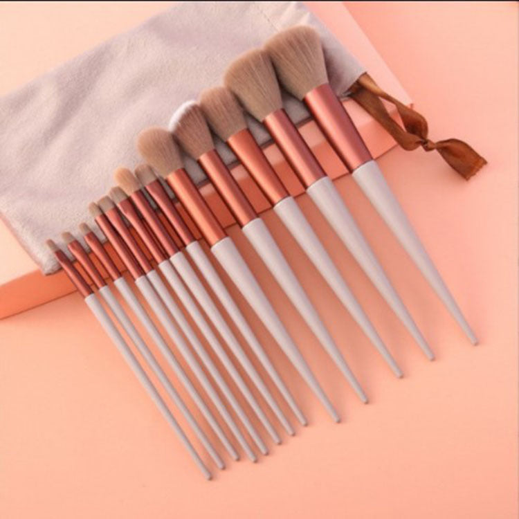 13-piece makeup brush set with beige handles, copper ferrules, and soft brown bristles, including a matching pouch.