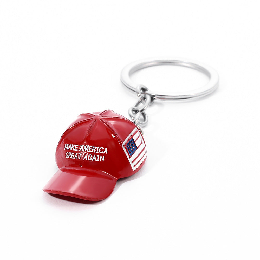 Red enamel "Make America Great Again" hat keychain with US flag detail on a silver metal keyring against white.