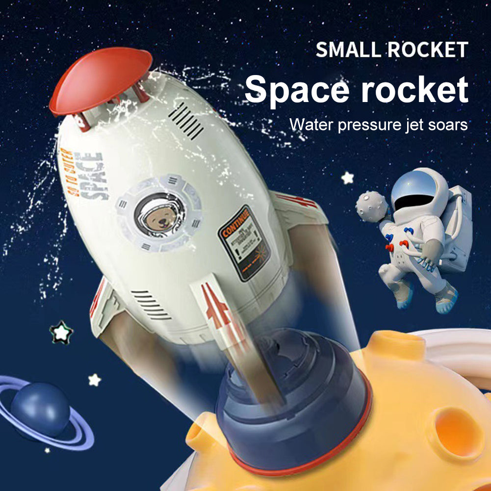 White plastic rocket water sprinkler toy with red top and astronaut decal, launching from a yellow planet-like base.