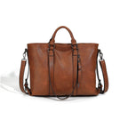 Brown soft leather tote bag with dual handles, side zipper detail, and an adjustable, detachable shoulder strap.
