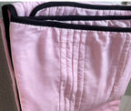 Soft pink cooling summer quilt with vertical stitching and contrasting black trim edges.