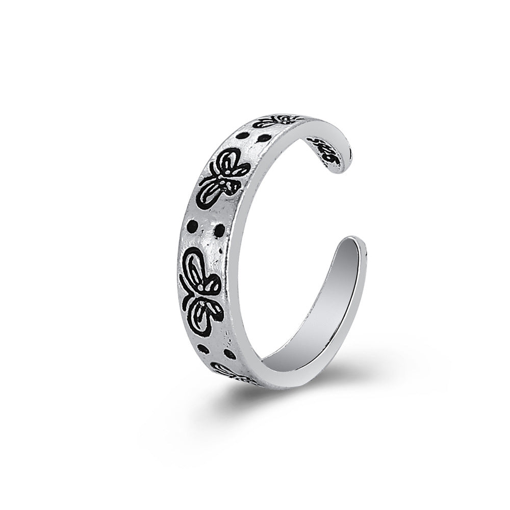 Silver-tone open ring with engraved black butterfly motifs and dots, featuring a vintage hip-hop aesthetic.