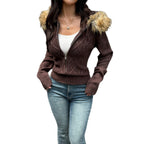 A woman wears a brown cable-knit, zip-up sweater coat with a faux fur-trimmed hood and rib-knit cuffs.