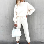 A woman wears a cream-colored long-sleeve fleece sweater set with a mock-neck top and drawstring joggers.