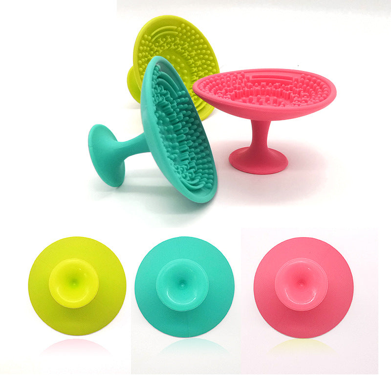 Pink, teal, and lime silicone makeup brush cleaning pads with textured scrubbing surfaces and suction cup bases.