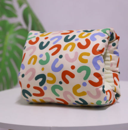 Washable cotton baby nursing arm pillow featuring a colorful, patterned U-shaped print on a cream background.
