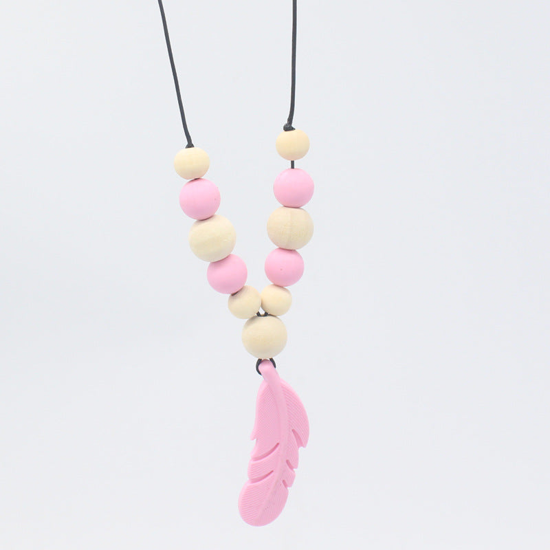 Baby teether necklace with pink silicone feather pendant and alternating natural wood and pink silicone beads.