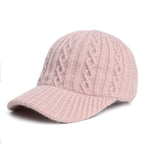 A light pink cable-knit wool baseball cap with a ribbed brim, isolated against a white background.