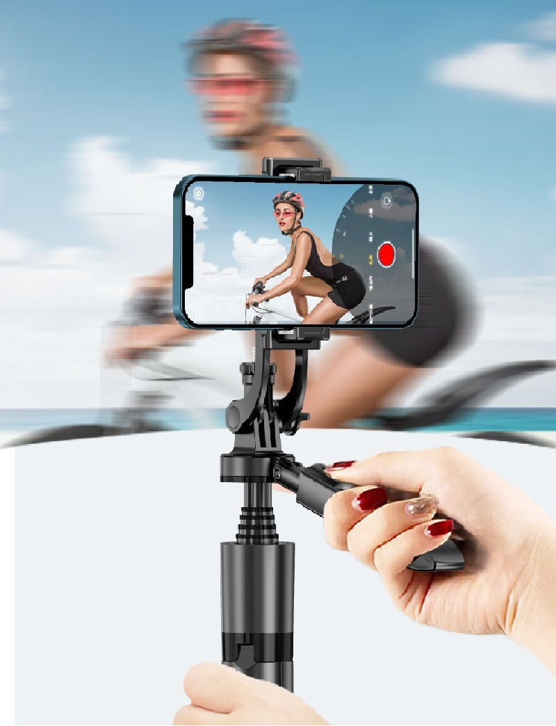 A black auto-tracking phone gimbal held by hand, showing a cyclist on the screen against a blurred outdoor background.