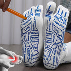 White reflexology socks with blue acupressure point labels, shown being massaged with an orange tool.