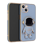 Blue matte phone case with a gold-trimmed 3D astronaut kickstand and camera cutout, featuring electroplated edges.