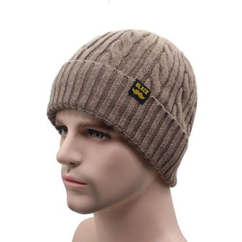 A brown cable-knit beanie with a ribbed cuff and a small black patch labeled "BLACK" worn by a mannequin.
