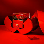 Red apple-shaped gift box with a drawer and clear case containing an eternal rose on a red background.