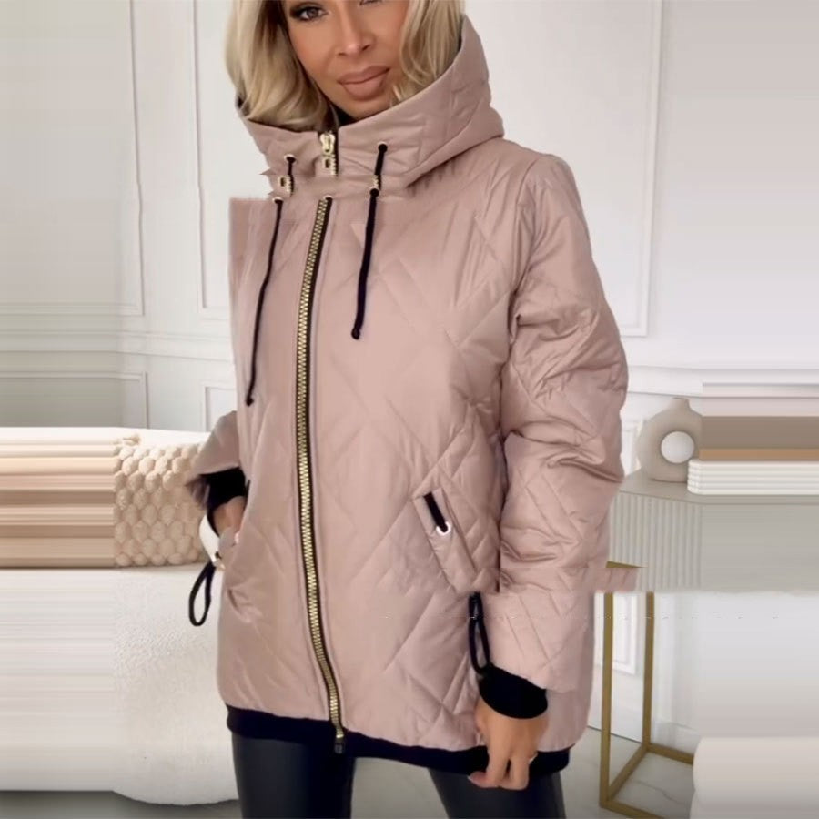 A woman wears a beige, diamond-quilted hooded jacket with a gold zipper and black drawstring accents.