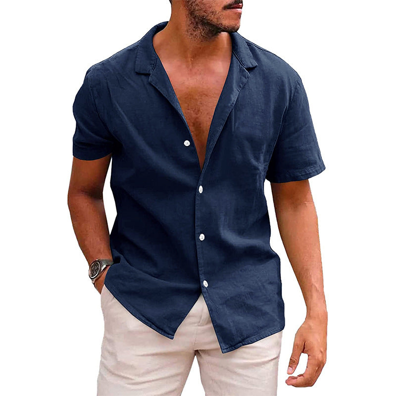 A man wearing a short-sleeve, navy blue linen button-down shirt with an open camp collar, paired with beige trousers.