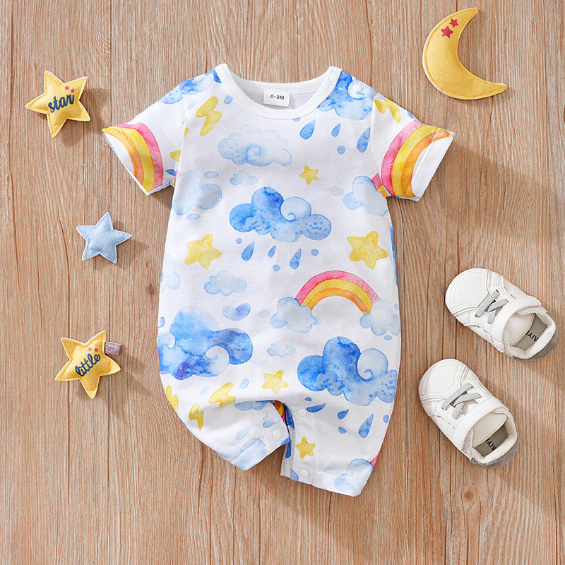 White short-sleeve baby romper with watercolor blue clouds, rainbows, yellow stars, and snaps on a wooden background.