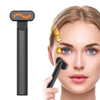 Black 4-in-1 LED red light therapy wand being used on a woman's face next to a drop of facial serum.