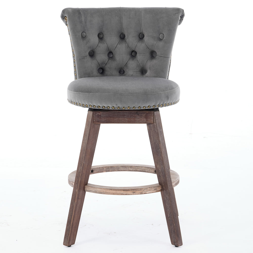Gray velvet counter stool with tufted back, nailhead trim, swivel seat, and rustic wood legs with a footrest ring.