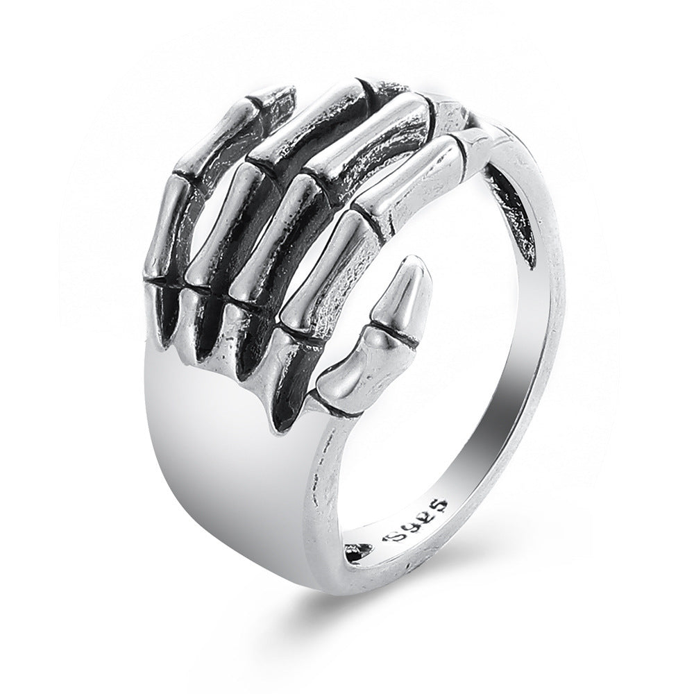Silver hip hop ring featuring a detailed skeleton hand wrapping around the finger, stamped S925 on the inner band.