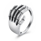 Silver hip hop ring featuring a detailed skeleton hand wrapping around the finger, stamped S925 on the inner band.