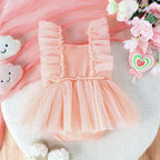 Peach baby jumpsuit with ruffle-trimmed straps and a sheer polka-dot tulle skirt overlay.