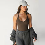 A woman wears a brown, ribbed, slim-fit racerback knitted vest with a V-neckline against a white background.