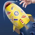 Yellow rocket water sprinkler toy with space-themed stickers and brown fins against a dark blue background.