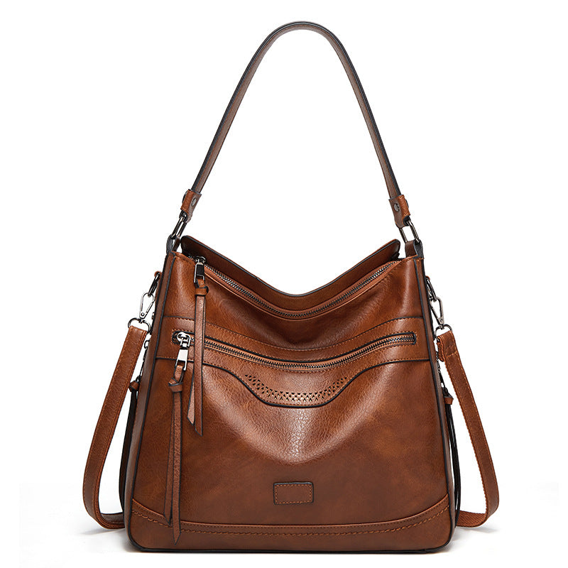 Brown vintage-style soft leather tote with zipper pockets, top handle, and detachable shoulder strap on white background.