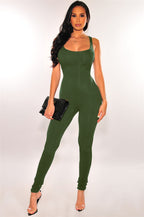 A woman wears a sleeveless, form-fitting olive green exercise jumpsuit with a scoop neck and full-length leggings.